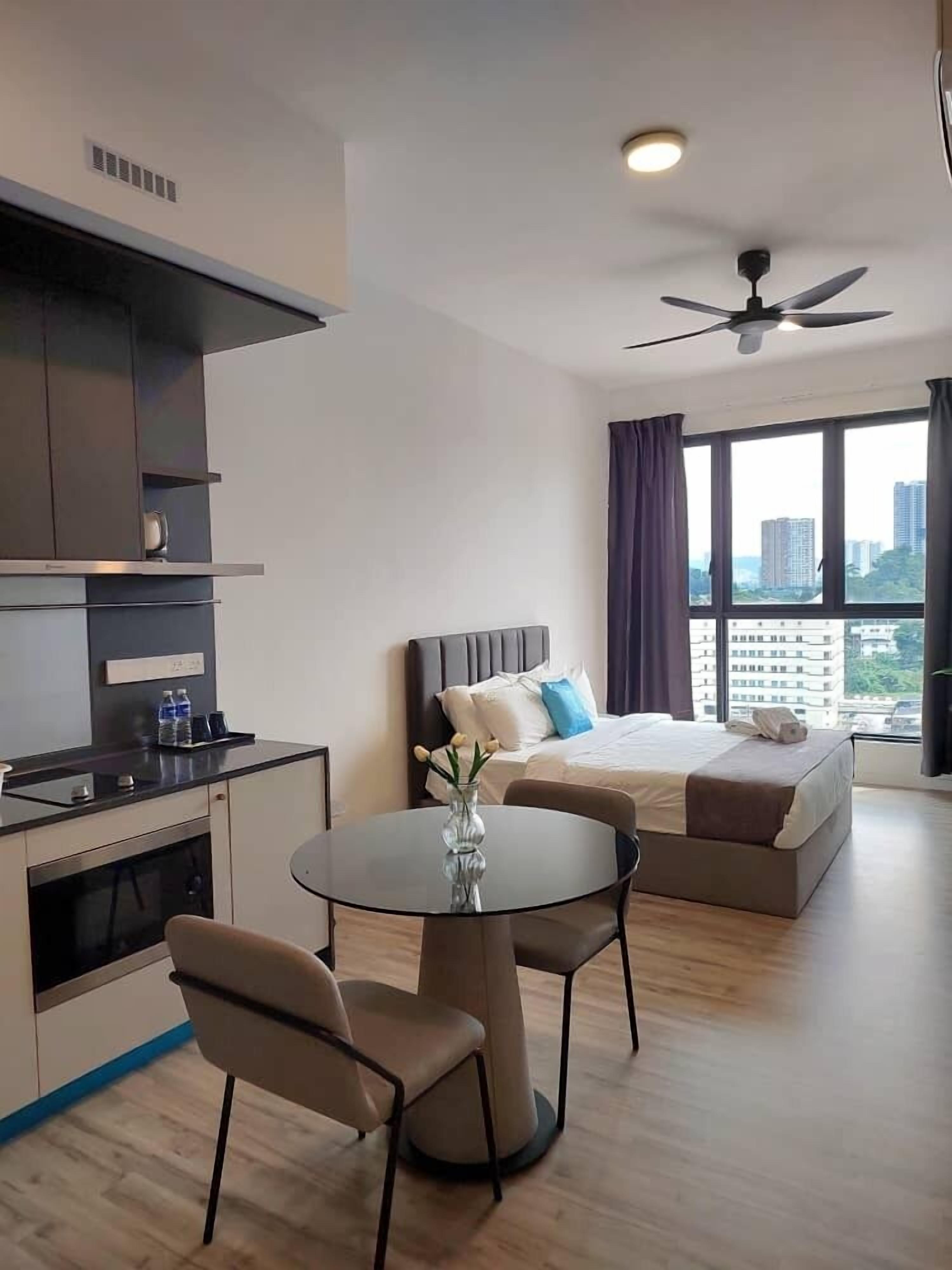 Une chambre d’hôtel moderne dotée d’une kitchenette, d’un lit avec vue, d’un coin repas et d’un ventilateur de plafond.