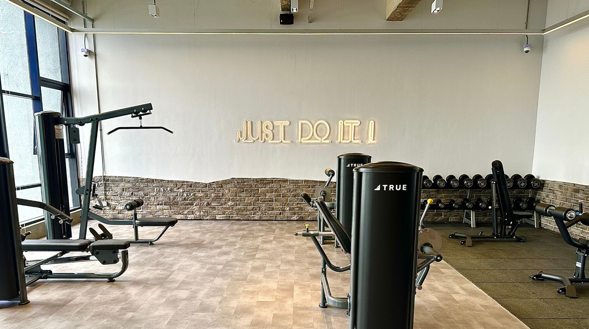 A gym with exercise equipment, a motivational wall, and a brick accent wall.