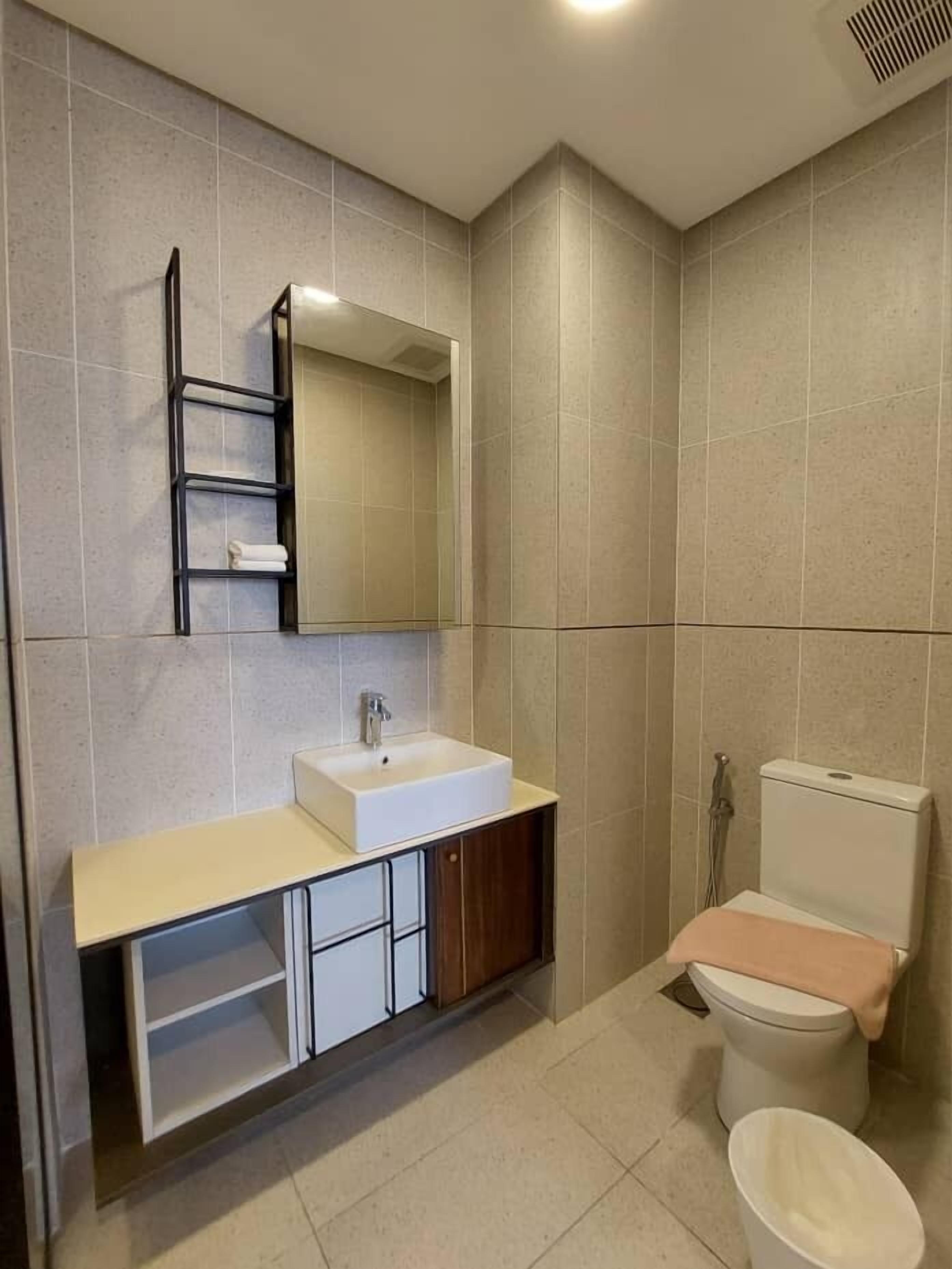 Un baño moderno con lavamanos, espejo y retrete blancos.