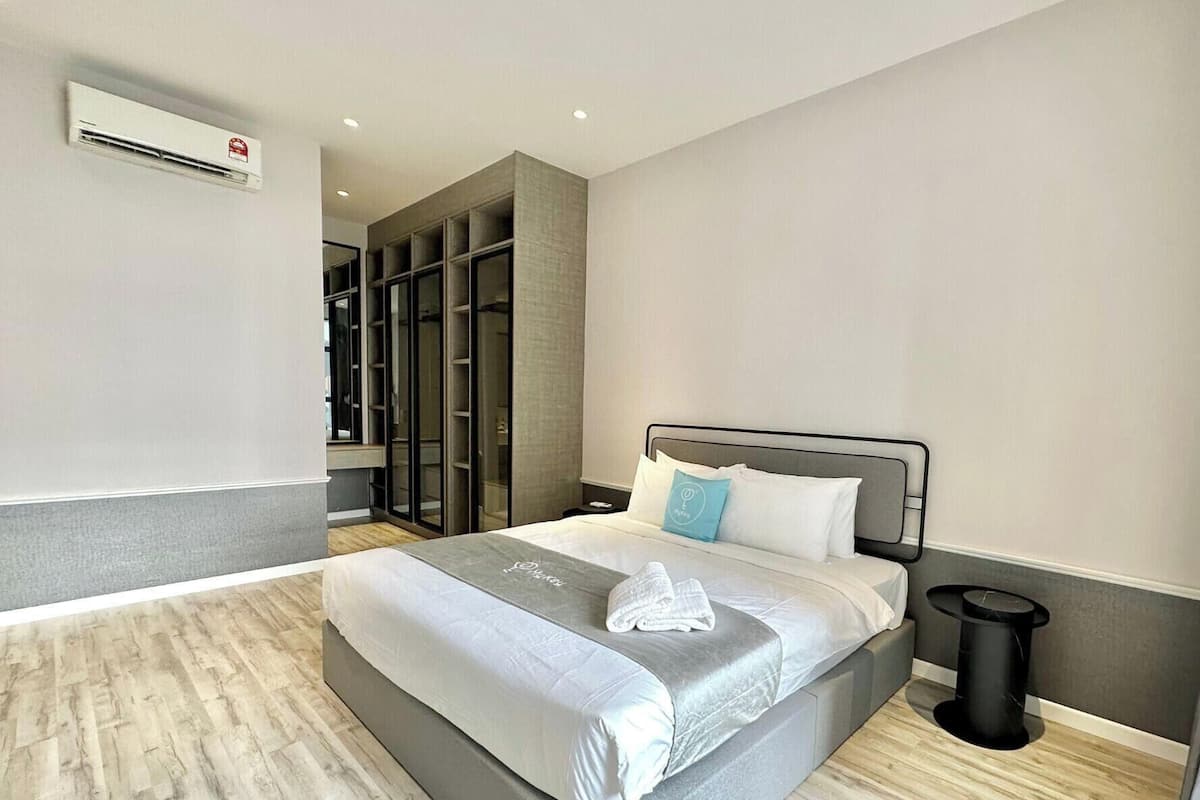 Una habitación de hotel moderna con una cama grande, armario empotrado y una mesita de noche pequeña.