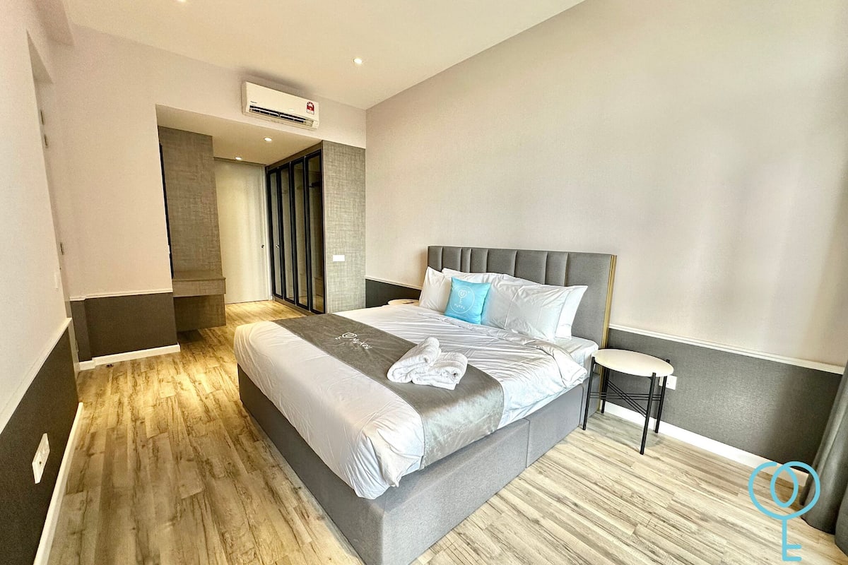 Una habitación de hotel moderna con una cama grande, una mesita de noche y un armario.