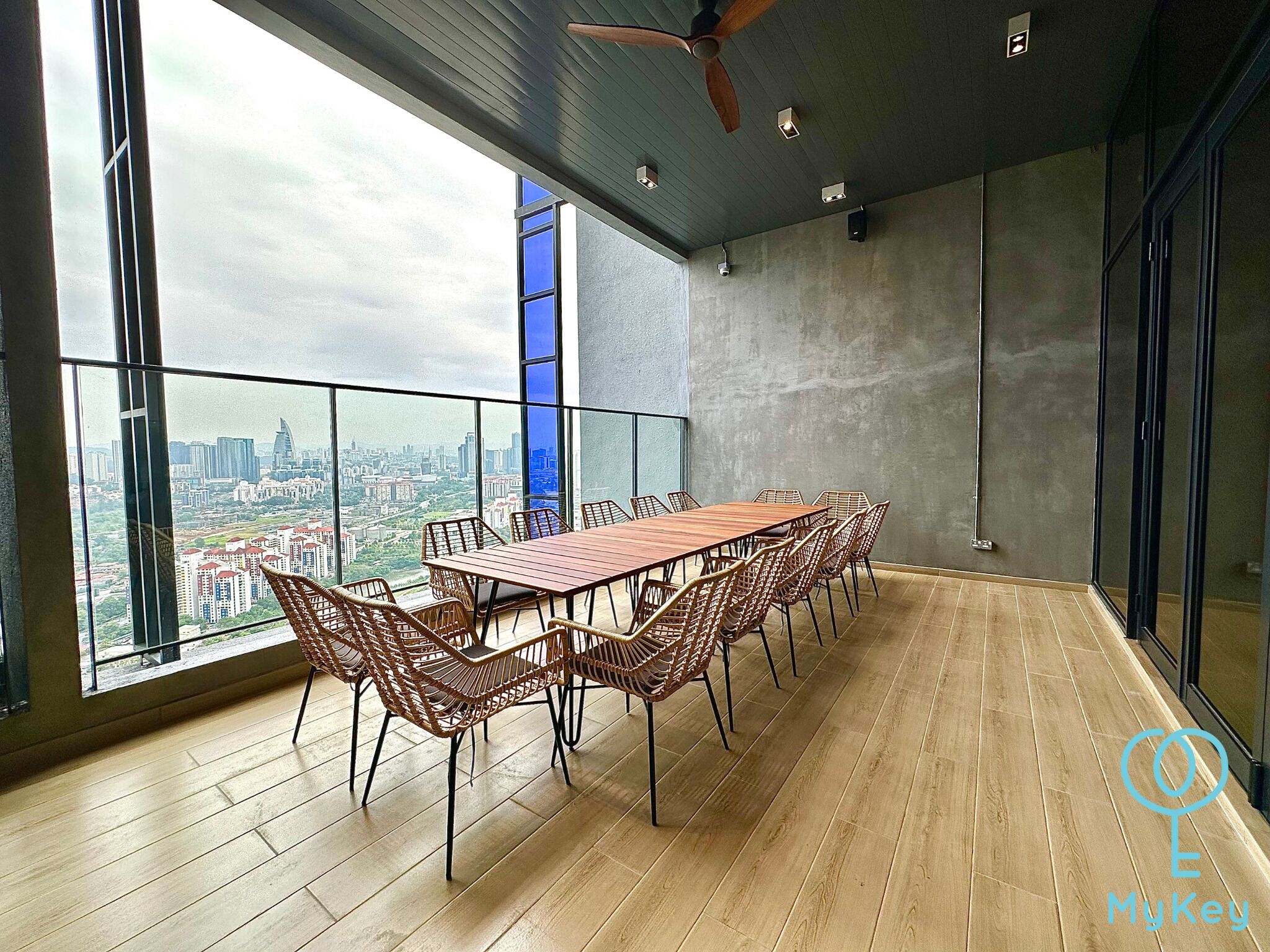 A spacious balcony with a long wooden table and wicker chairs, offering a city view.