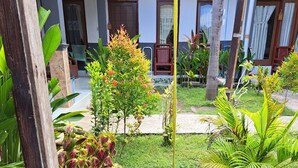 Un jardín con una hamaca, un banco de madera y una casa al fondo.