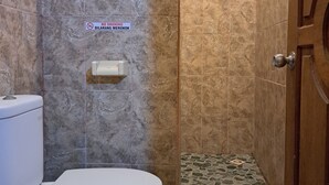 Un baño con inodoro, zona de ducha y suelo de baldosas.