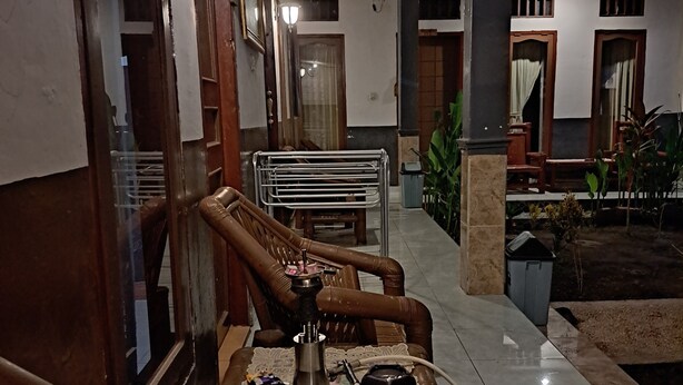 Un sofá de madera tradicional con estructura metálica, un narguilé sobre una mesa y un piso de baldosas.