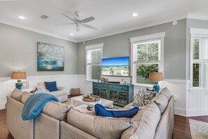 A living room with a sectional sofa, a television, and a decorative cabinet.