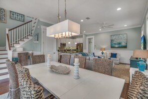A spacious living room with a dining area, a kitchen in the background, and a staircase leading to another level.
