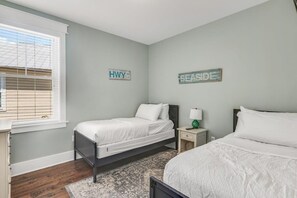 A bedroom with two beds, a nightstand, a lamp, and two wall signs.