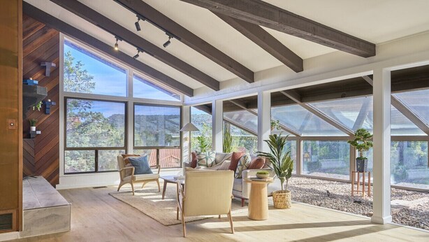 A spacious room with large windows, wooden beams, and a mix of seating areas. - Mid-Century Home in the Heart of Sedona (Sedona)