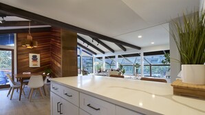 A modern kitchen with a large island, wooden accents, and large windows. - Mid-Century Home in the Heart of Sedona (Sedona)
