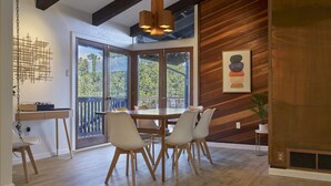 A dining area with a wooden table and chairs, a view through glass doors to an outdoor deck, and a modern art piece on the wall. - Mid-Century Home in the Heart of Sedona (Sedona)