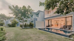 A modern house with a swimming pool, a glass-enclosed patio, and a well-maintained lawn.