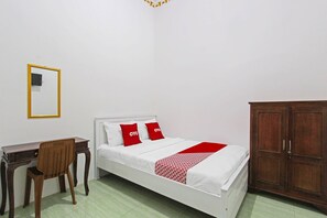 Quarto com uma cama, uma cadeira de madeira, uma escrivaninha e um guarda-roupa.
