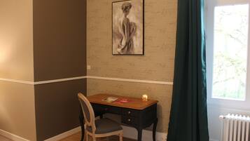 A room with a desk, chair, and a painting on the wall.