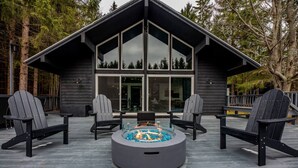 A modern cabin with a deck, two Adirondack chairs, and a glass-top fire pit. - Finger Lakes Escape • FLX Chalet + Private Pond (Branchport)