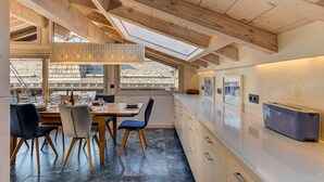 A modern kitchen with wooden beams, a large window, and a built-in oven.
