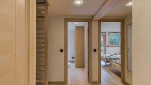 A modern interior with wooden floors, a staircase, and a bed with a view of trees.