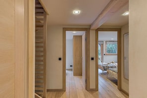 Un intérieur moderne avec des planchers en bois, un escalier et un lit donnant sur la forêt.