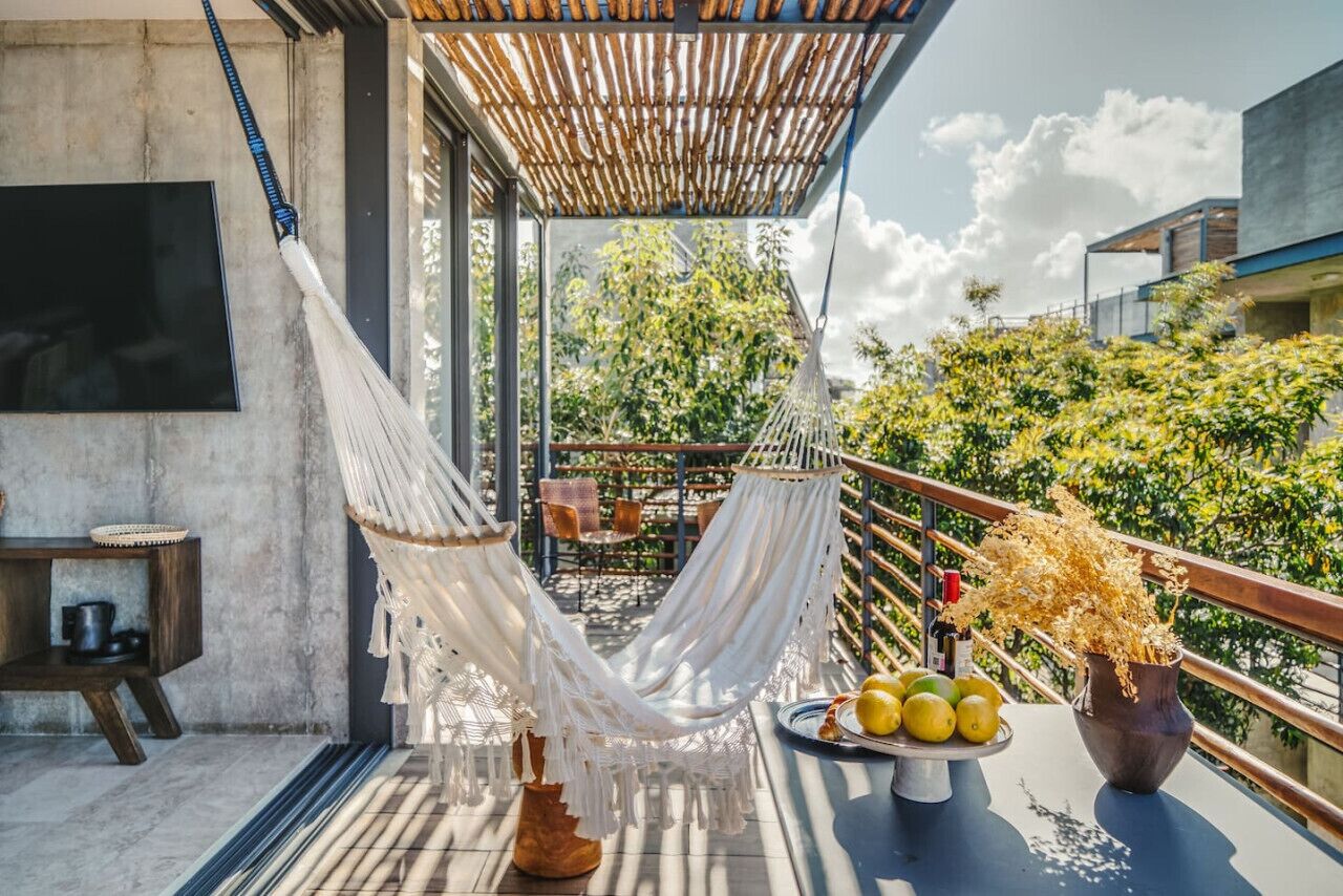 Eine Hängematte auf einem Balkon mit Blick auf Bäume und ein Gebäude.