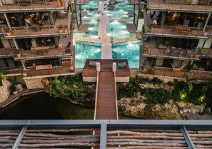 A multi-level hotel with a central pool, outdoor seating, and a wooden deck. - Tulum Luxury 2BR PH w Private Pool| Private Cenote (Tulum)