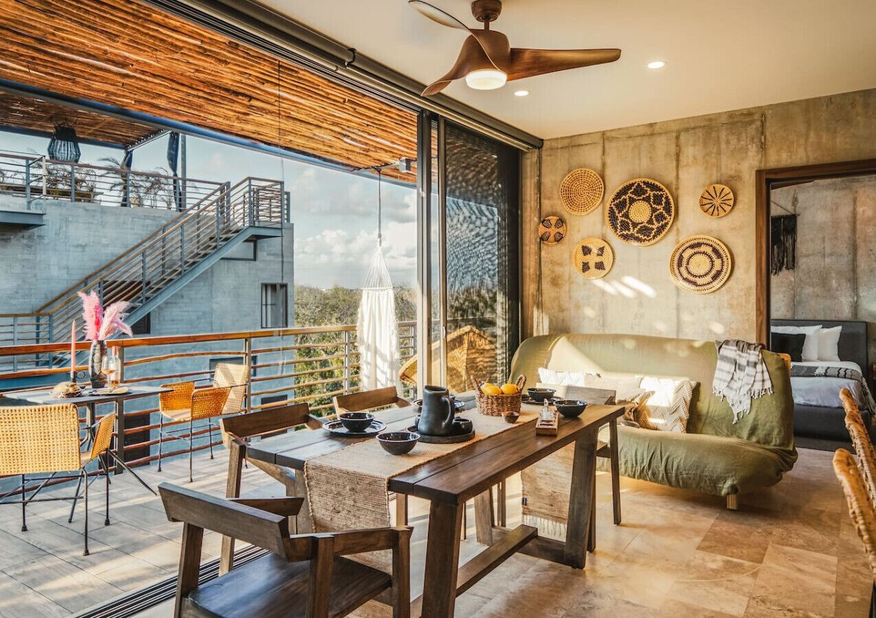 A modern interior with a dining area, a sofa, and a staircase leading to an outdoor terrace.