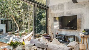 A modern living room with a large TV, a fireplace, and a poolside area with lounge chairs.
