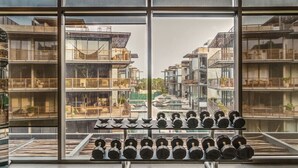 A gym with a view of a residential building through large windows.
