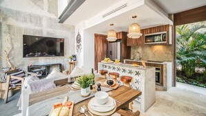 A modern kitchen with a central island, pendant lighting, and a large TV mounted on the wall.