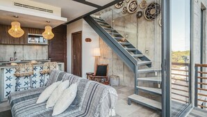 A modern interior with a sofa, a staircase, and wall decor. - Tulum Paradise: Penthouse w/ Private Pool & Cenote (Tulum)