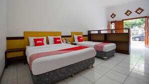A hotel room with two beds, each with a red and white bedspread, and a wooden headboard.