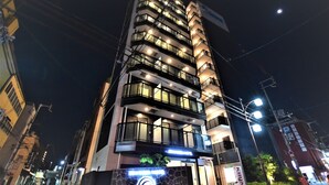 Un hôtel à plusieurs étages, doté de balcons, d'une enseigne au néon et d'une façade en pierre.