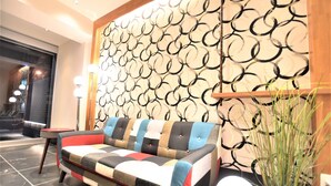 Un espace de vie moderne comprenant un canapé, une petite table et un mur décoratif orné de motifs circulaires.