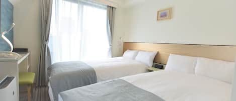A hotel room with two beds, a desk, and a chair.