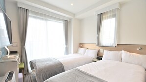 Une chambre d’hôtel avec deux lits, un bureau avec un téléphone et un miroir au-dessus du lit.