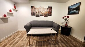 Relax in this stylish living room with a sofa, artworks, and a vase with flowers on a light-colored floor.