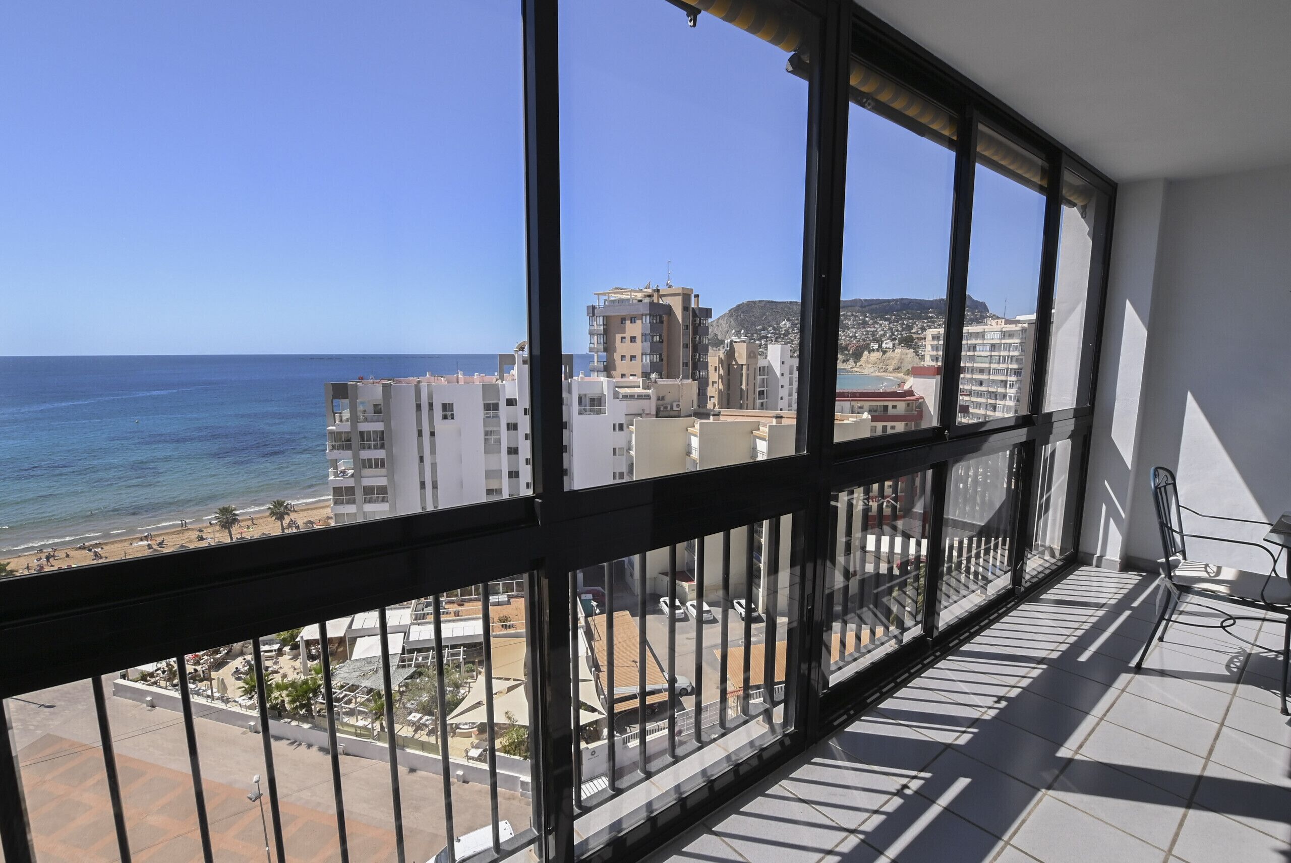A balcony with a view of the sea and buildings.