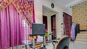 Une pièce comprenant un bureau, un ordinateur portable, une chaise et des rideaux décoratifs.