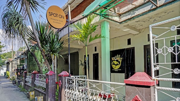Un bâtiment avec une enseigne indiquant « SPOT ON PONDOK ELIA SYARIAH » et un logo sur la porte.