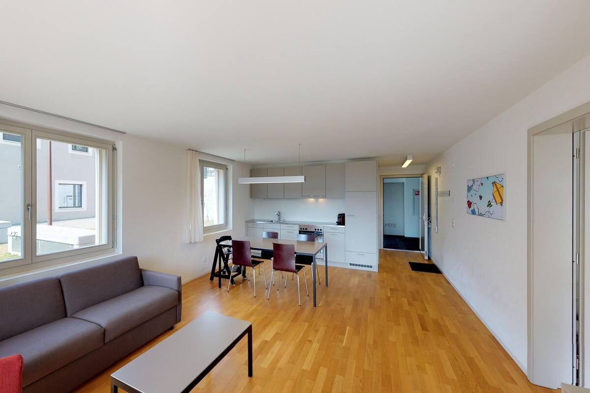 A modern apartment with a living room, dining area, and kitchen.