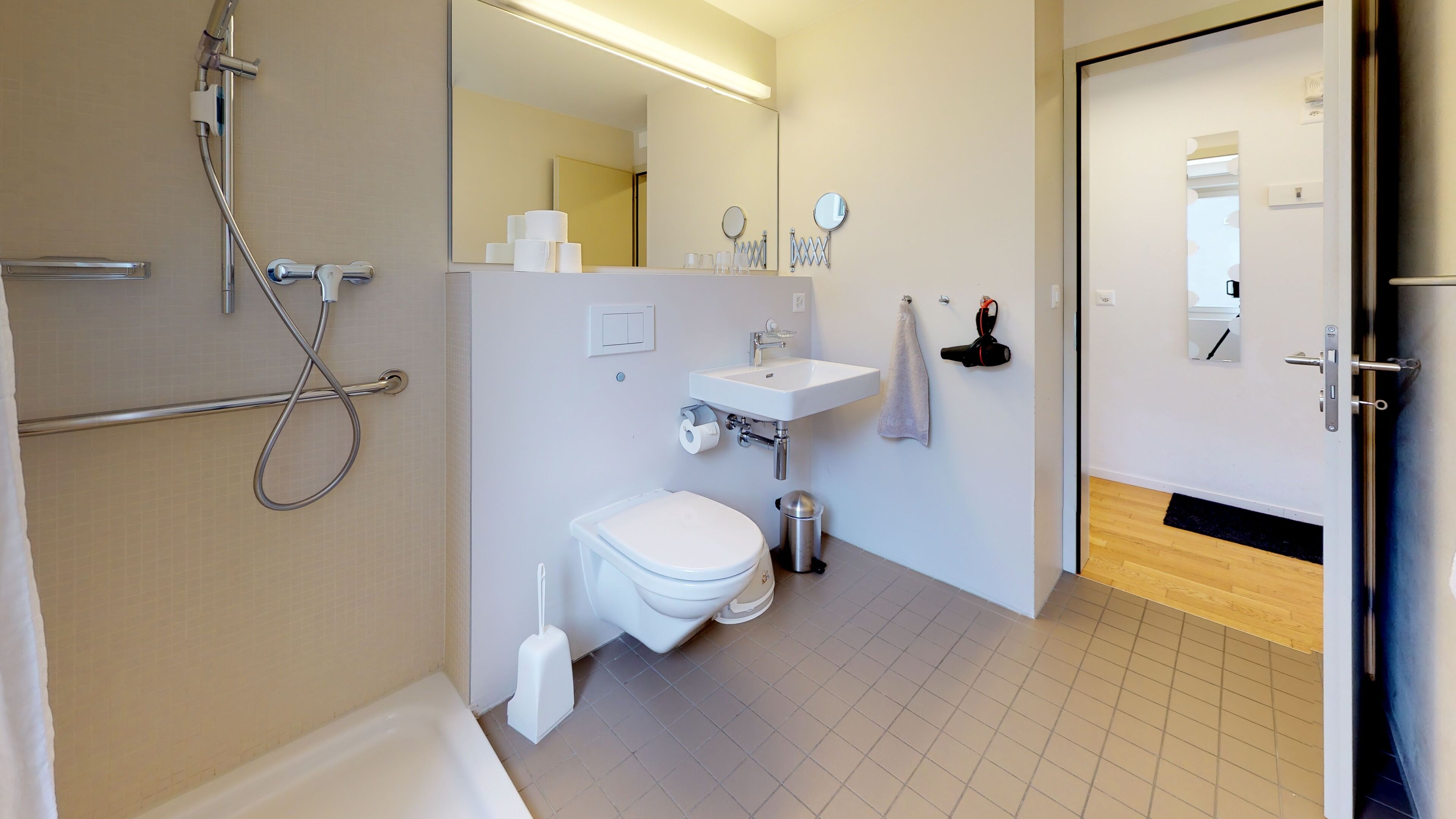 A modern bathroom with a shower, toilet, sink, and mirror.