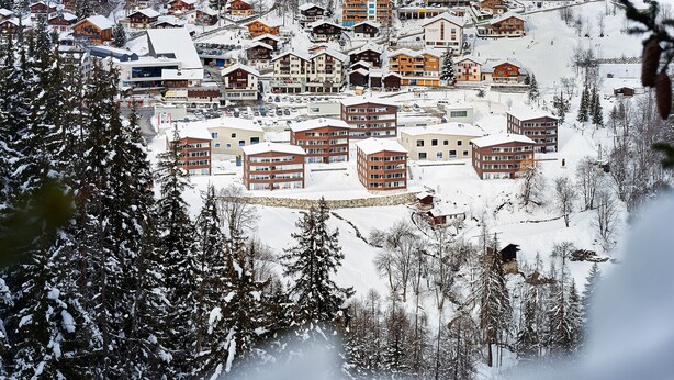 A snow-covered town with multiple buildings, including several multi-story structures with balconies. - Reka-Feriendorf Blatten-Belalp (Naters)