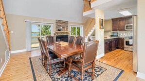Uma sala de jantar espaçosa com uma grande mesa de madeira e cadeiras, lareira e vista para o exterior.