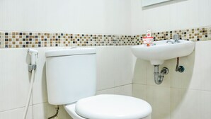 A bathroom with a toilet, sink, and tiled backsplash.