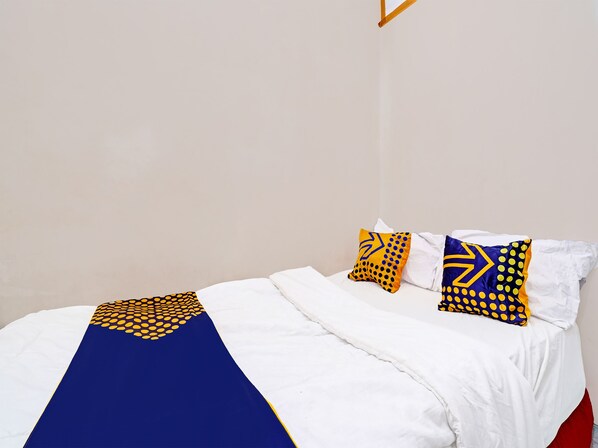 A neatly made bed with white bedding and a blue and yellow patterned throw. - OYO Life 91589 Bunda Homestay Syariah (Bandung)