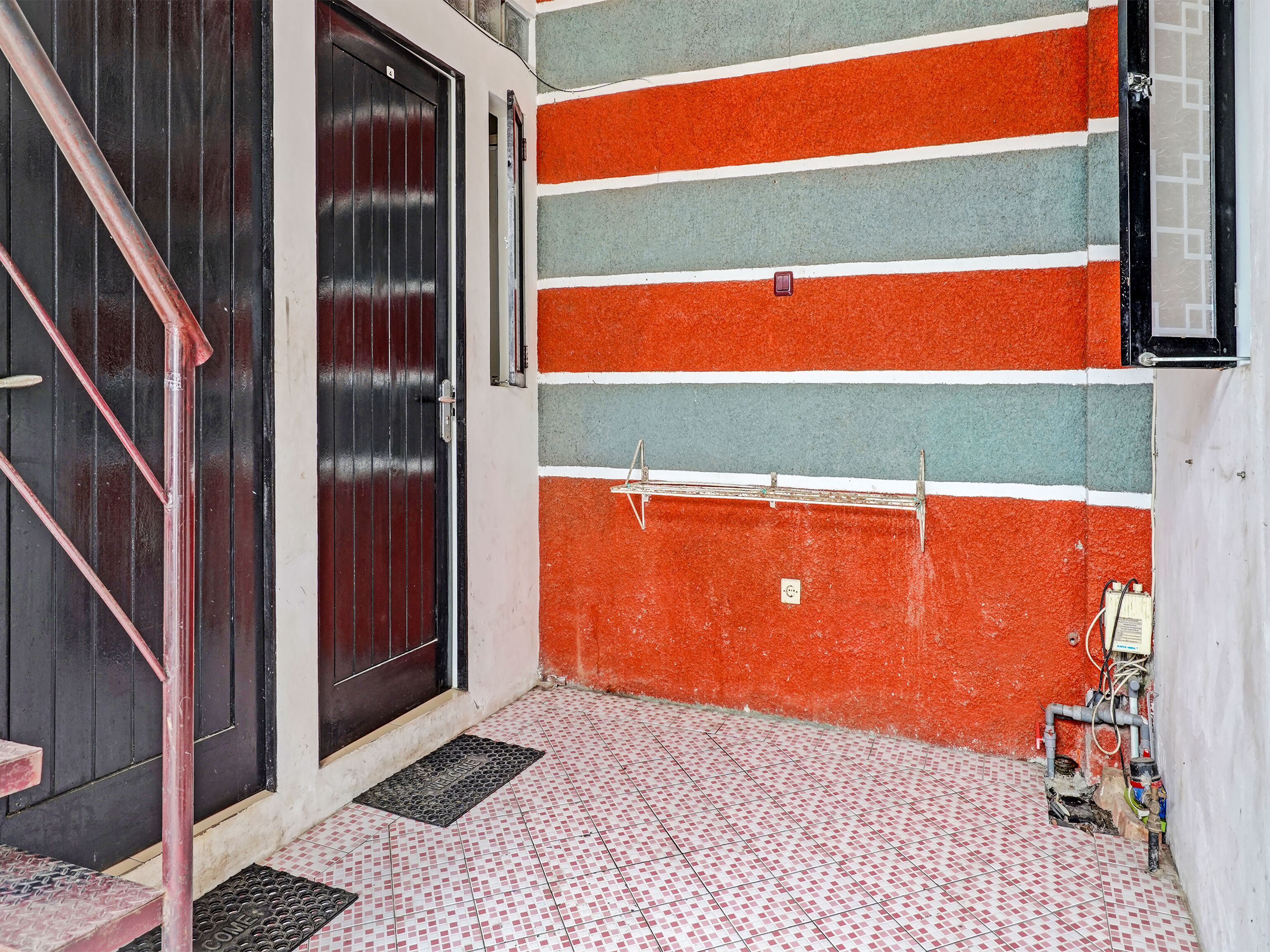 A tiled floor with a metal grate in front of a door.