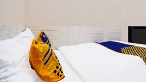A neatly made bed with white bedding and a blue and yellow patterned blanket.