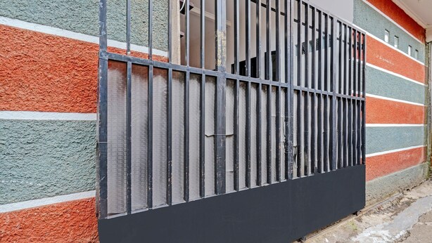 A black metal gate with vertical bars, attached to a wall with colorful horizontal stripes.