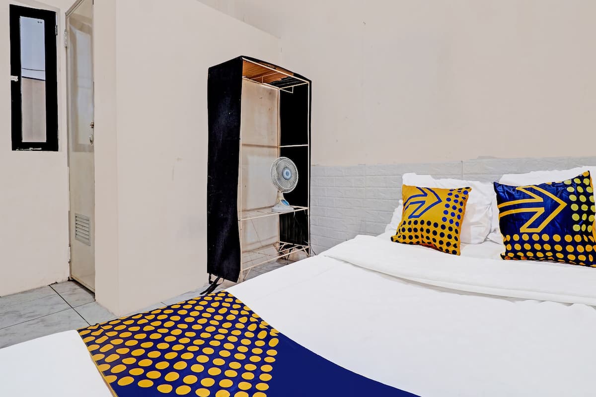 Une chambre à coucher avec un lit, une armoire et un ventilateur.