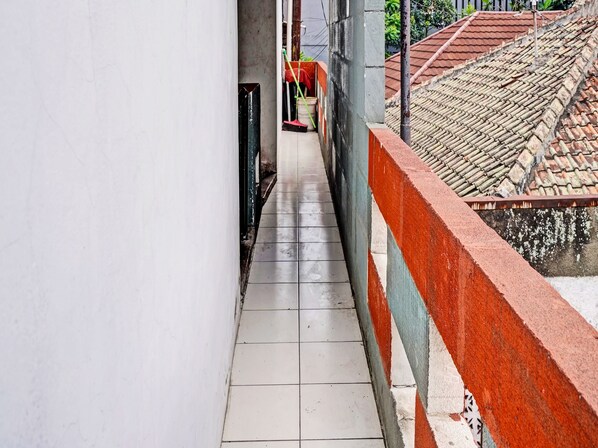 Un estrecho pasillo con baldosas, con una pared de color rojo y blanco a un lado y un techo con baldosas a la vista en el otro.
