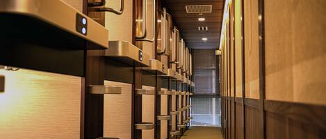 A hotel corridor with rows of lockers and a wooden wall.